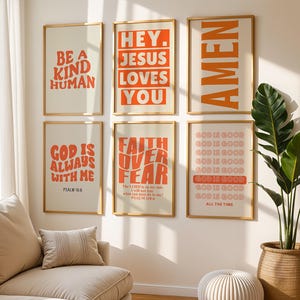May include: Six framed art prints with inspirational quotes in orange text on a cream background. The prints include phrases like "Be a Kind Human" and "Hey Jesus Loves You". The frames have a gold finish.