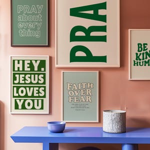 Op de afbeelding: Een verzameling ingelijste kunstafdrukken met inspirerende citaten. De prints bevatten zinnen als "PRAY", "HEY. JESUS LOVES YOU" en "FAITH OVER FEAR". Het kleurenpalet omvat groen, wit en een zachte roze achtergrond.