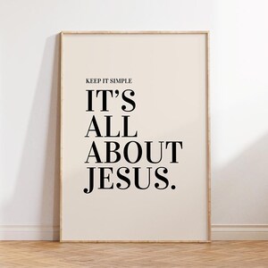 K&ouml;nnte beinhalten: Ein gerahmter Druck mit dem Text "KEEP IT SIMPLE IT'S ALL ABOUT JESUS." Der Text ist in einer fetten, schwarzen Serifenschrift auf cremefarbenem Hintergrund. Der Rahmen hat eine helle Holzfarbe.