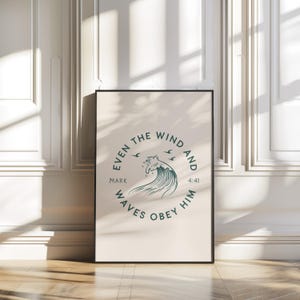 May include: A framed print with the text "Even the Wind and Waves Obey Him" in a circular design. The design features a stylized wave and birds in teal against a cream background. The frame is black.