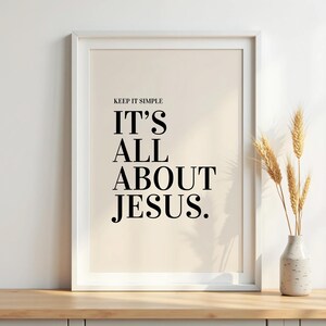 K&ouml;nnte beinhalten: Gerahmter Druck mit dem Text "KEEP IT SIMPLE IT'S ALL ABOUT JESUS" in Schwarz auf cremefarbenem Hintergrund. Rechts vom Rahmen befindet sich eine kleine Vase mit Weizen&auml;hren.
