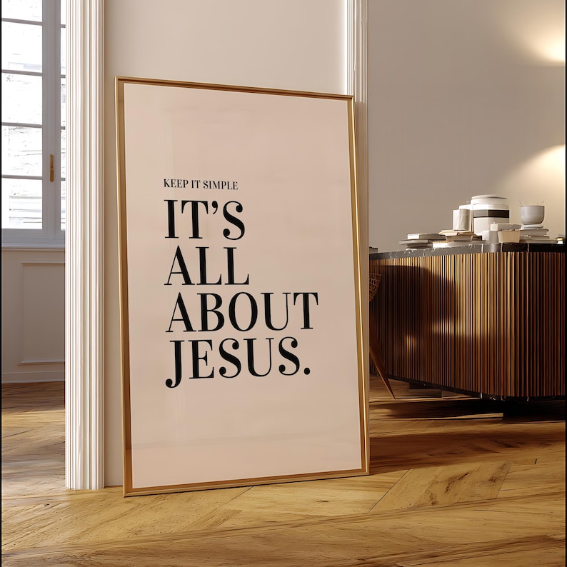 K&ouml;nnte beinhalten: Ein gerahmter Druck mit dem Text "KEEP IT SIMPLE IT'S ALL ABOUT JESUS." Der Druck hat einen goldenen Rahmen und lehnt an einem wei&szlig;en T&uuml;rrahmen. Der Hintergrund umfasst einen Holzboden und einen Holzschrank.
