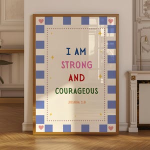 Könnte beinhalten: Ein rechteckiger Wandkunstdruck in einem goldenen Rahmen mit dem Text I AM STRONG AND COURAGEOUS JOSHUA 1:9 in Blau, Pink, Rot und Grün. Der Rand hat ein blau-weißes Karomuster mit kleinen pinken Herzen und gelben Sternen.
