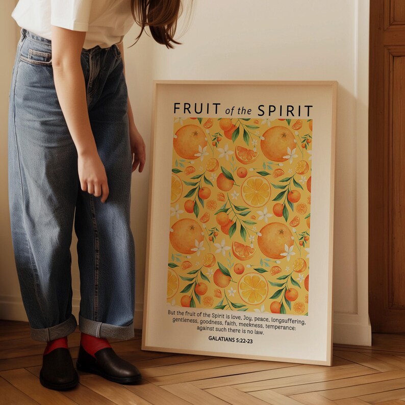 May include: A framed print with a yellow background and a repeating pattern of orange slices, white flowers, and green leaves. The print has the text "FRUIT of the SPIRIT" at the top and a Bible verse from Galatians 5:22-23 at the bottom.