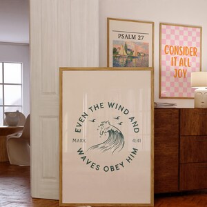 May include: Three framed art prints. The largest print has a circular design with text and a wave illustration. The other prints feature text and a landscape painting. The frames are a light brown color.