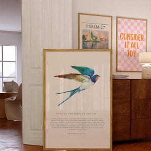 Peut inclure: Une peinture à l'aquarelle d'une hirondelle bleue et verte en vol sur un fond rose pâle. La peinture est encadrée et comprend une citation de Matthieu 6 :25-26 sur le fait de ne pas s'inquiéter de sa vie, mais de regarder les oiseaux du ciel. Le texte "Regardez les oiseaux du ciel" est imprimé en noir au bas de la peinture.