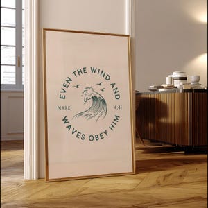 May include: A framed print with a gold border, leaning against a wall. The print features a circular design with the text "EVEN THE WIND AND WAVES OBEY HIM" and a stylized wave illustration in teal. The text "MARK 4:41" is also included.