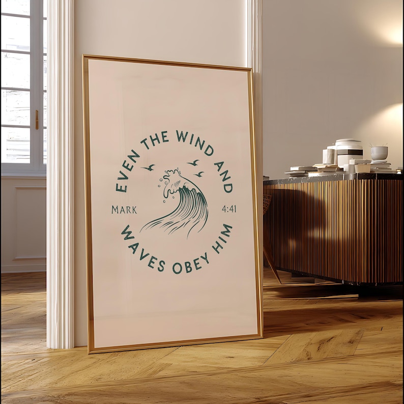 May include: A framed print with a gold border, leaning against a wall. The print features a circular design with the text "EVEN THE WIND AND WAVES OBEY HIM" and a stylized wave illustration in teal. The text "MARK 4:41" is also included.