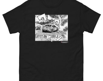 May include: A black short-sleeved t-shirt featuring a square graphic print on the chest. The print is a black and white manga-style illustration of a sports car drifting on a winding road, accompanied by Japanese sound effect characters and text.