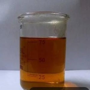 Könnte beinhalten: Ein transparentes Glas-Becherglas gefüllt mit einer goldgelben Flüssigkeit, gekennzeichnet mit Messungen in Millilitern. Der Flüssigkeitsstand liegt zwischen 50 und 75 Millilitern.