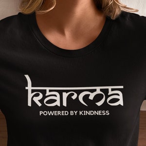May include: Black t-shirt with white text that reads "karma" in a stylized font and "powered by kindness" below it.