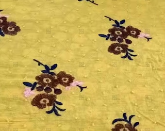 May include: Yellow fabric with a subtle dotted pattern and embroidered brown and pink flowers with black stems.