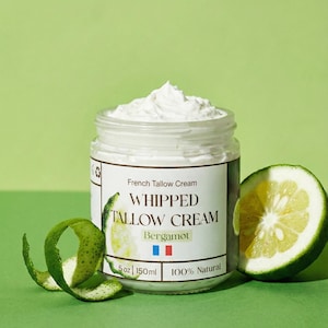 Op de afbeelding: Een pot Franse Talgcrème, met het opschrift "Whipped Tallow Cream Bergamot", met een toefje crème erop. Een in plakjes gesneden citrusvrucht en een groene schilkrul liggen naast de pot. Het etiket geeft 150ml en 100% natuurlijk aan.