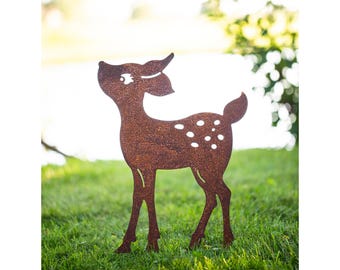 May include: A rusty metal silhouette of a fawn with white spots standing in a grassy area.