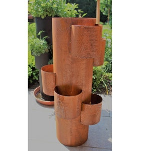 Peut inclure: Un pot de fleurs en métal rouillé à plusieurs niveaux pour planter des fleurs ou des herbes. Le pot est fait d'une seule pièce de métal et a une forme cylindrique.