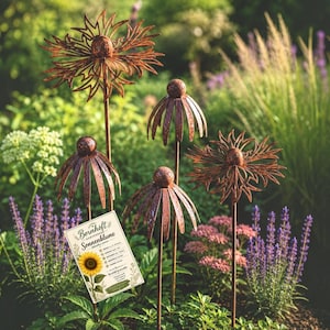 Könnte beinhalten: Vier rostfarbene Metall-Gartenstecker in Blumenform mit kugelförmigen Zentren und dünnen Stielen. Ein rechteckiges weißes Etikett ist befestigt, das den Text "Bernhoft" und "Sonnenblume" sowie eine Sonnenblumen-Illustration zeigt.
