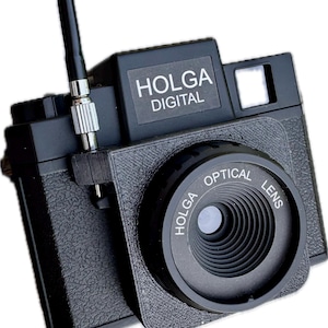Op de afbeelding: Een zwarte Holga Digital camera met een getextureerde behuizing, een opvallende ronde lensbehuizing met het opschrift Holga Optical Lens en een rechthoekig bovendeel met de tekst Holga Digital. Een dunne zwarte antenne steekt naar boven uit.