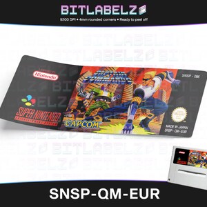 Könnte beinhalten: Ein schwarzes und weißes Super Nintendo-Spielkartuschen-Etikett für das Spiel "Street Fighter 2 Turbo: Hyper Fighting". Das Etikett zeigt ein farbenfrohes Bild der Spielfiguren, darunter Ryu, Ken und Chun-Li, in Kampfpose. Das Etikett enthält auch den Spieltitel, das Super Nintendo-Logo und das Capcom-Logo. Das Etikett ist auf hochwertigem, glänzendem Papier gedruckt und für Langlebigkeit und Strapazierfähigkeit ausgelegt. SNSP-QM-EUR