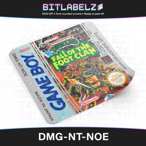 Könnte beinhalten: Ein weiß-blaues Game Boy-Cartridge-Etikett mit dem Text "Game Boy" und "Made in Japan". Das Etikett zeigt ein farbenfrohes Bild der Teenage Mutant Ninja Turtles aus dem Videospiel "Teenage Mutant Ninja Turtles: Fall of the Foot Clan". Der Text "KONAMI" und "Original Nintendo Seal of Quality" ist ebenfalls auf dem Etikett zu sehen.