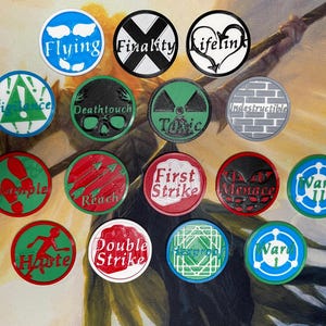 May include: A collection of colorful, circular game tokens with various text and graphic designs. The tokens feature words like "Flying," "Finality," "Lifelink," "Deathtouch," and "First Strike." The tokens are in various colors, including blue, green, red, and black.
