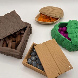 May include: A collection of miniature, textured containers in various shapes and colors. One is a wooden chest filled with brown rectangular pieces. Another is a leaf-shaped container with purple spheres. Other containers hold orange gems and gray stones.