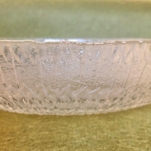 May include: A clear glass bowl with a textured, frosted finish. The bowl has a rounded shape and a wide rim.