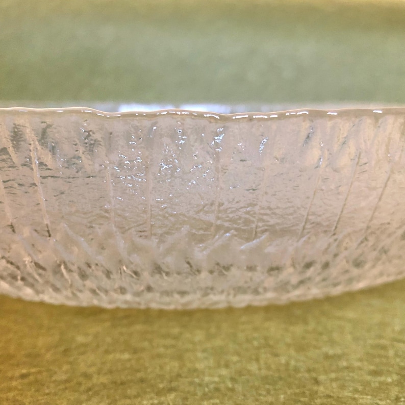 May include: A clear glass bowl with a textured, frosted finish. The bowl has a rounded shape and a wide rim.