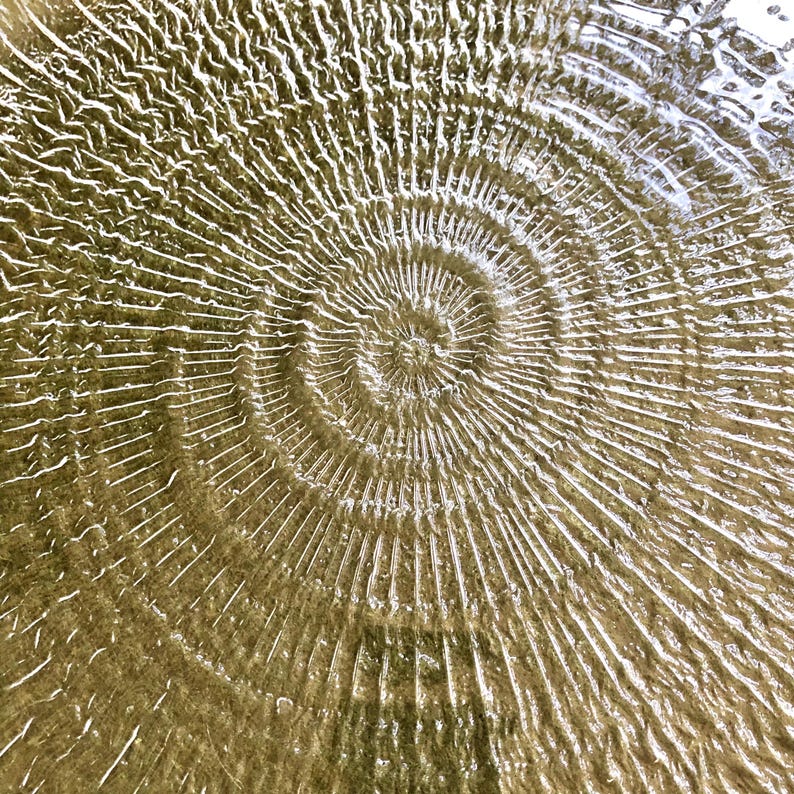May include: A close-up of a swirling pattern in water, creating a ripple effect with concentric circles.