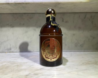 May include: A brown glass bottle of perfume with a gold cap and a gold label that says "Exquisis Guerlain".