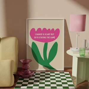 Könnte beinhalten: Ein gerahmter Druck mit einem rosa Blumendesign und dem Text "CHANGE IS SCARY BUT SO IS STAYING THE SAME" steht auf einem Holzboden. Ein grün-weiß karierter Teppich liegt vor dem Druck. Ein gelbes Sofa und eine rosa Lampe sind ebenfalls im Raum.