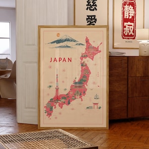 May include: A framed vintage-style map of Japan, featuring a red and pink outline of the islands with illustrations of landmarks. The word "JAPAN" is printed in a bold font. The map is in a wooden frame.