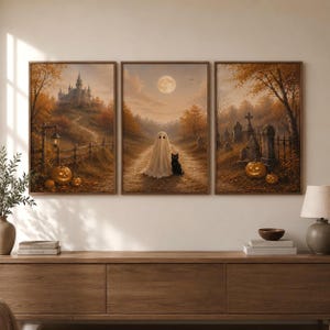 May include: A triptych of framed wall art prints featuring a Halloween theme. The left panel shows a castle on a hill with pumpkins. The center panel depicts a ghost and a black cat on a path under a full moon. The right panel shows a graveyard.