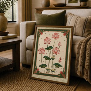 May include: A rectangular framed wall art piece featuring a botanical illustration of pink lotus flowers and green lily pads on a cream background, enclosed by a dark green border with small red floral accents in each of the four corners.