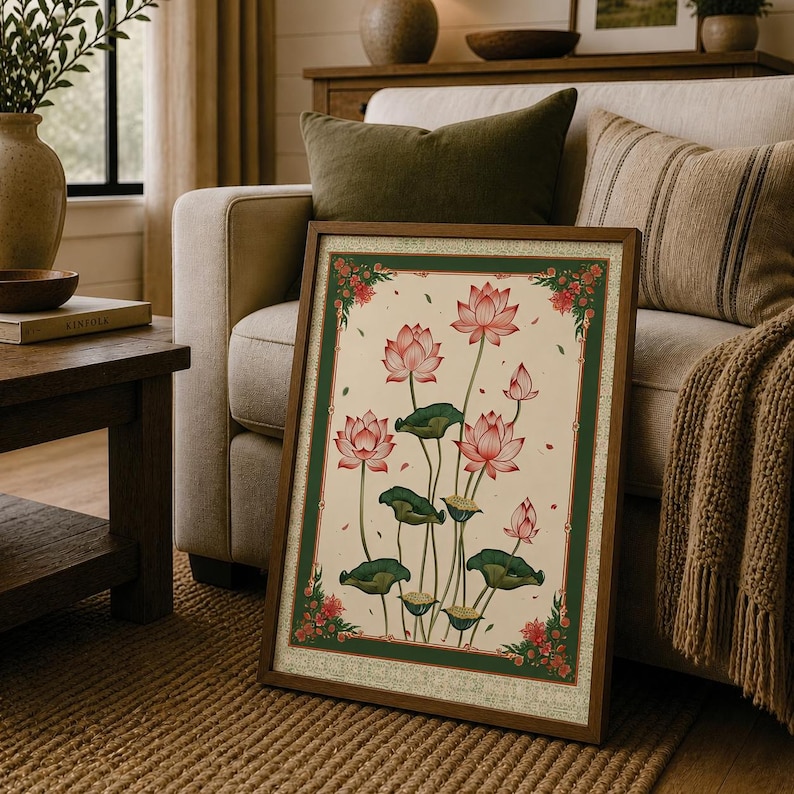 May include: A rectangular framed wall art piece featuring a botanical illustration of pink lotus flowers and green lily pads on a cream background, enclosed by a dark green border with small red floral accents in each of the four corners.