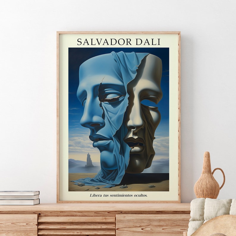 Op de afbeelding: Een ingelijste poster met een surrealistisch schilderij van Salvador Dali. Het schilderij toont twee gezichten, waarvan er &eacute;&eacute;n gedeeltelijk bedekt is met een blauwe doek, met een rotsachtig landschap op de achtergrond. De tekst "Libera tus sentimientos ocultos" is onder het schilderij gedrukt.