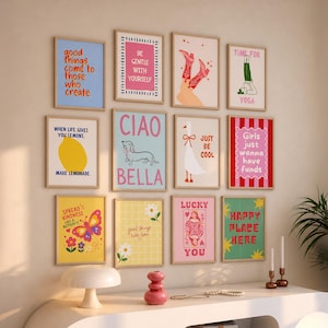 May include: A gallery wall of twelve framed art prints featuring various colorful illustrations and text, including phrases like Good things come to those who create, Be gentle with yourself, Ciao Bella, Time for yoga, and Girls just wanna have funds.