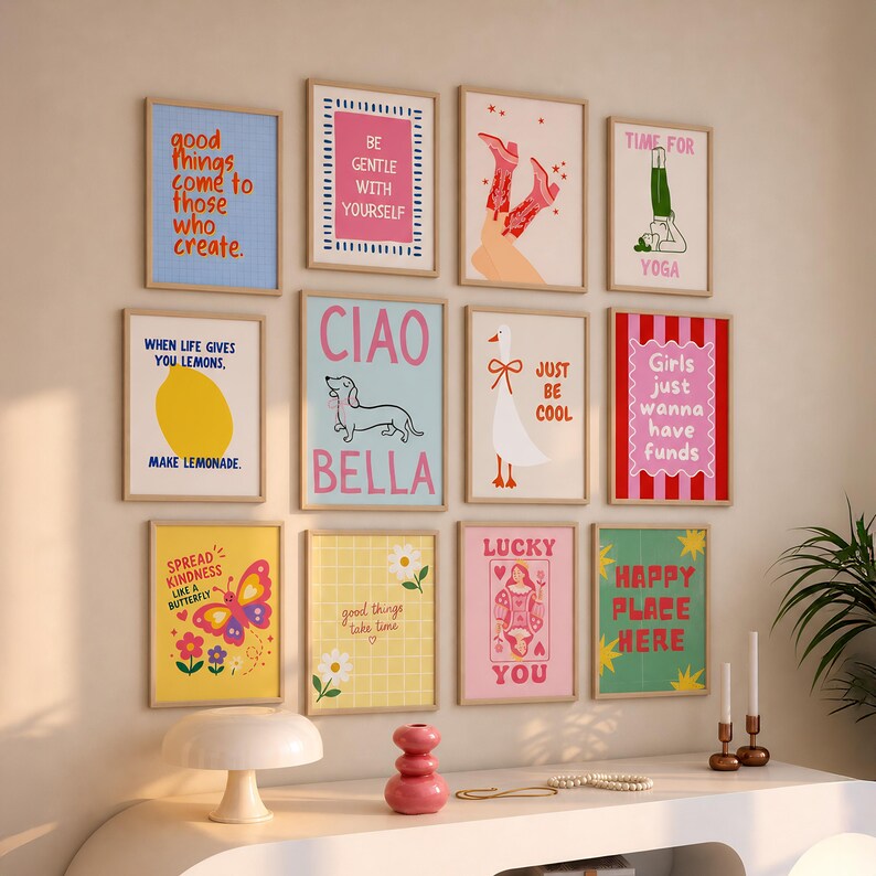 May include: A gallery wall of twelve framed art prints featuring various colorful illustrations and text, including phrases like Good things come to those who create, Be gentle with yourself, Ciao Bella, Time for yoga, and Girls just wanna have funds.