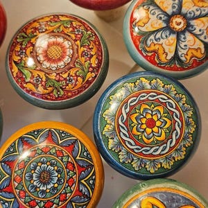 May include: Six colorful ceramic bottle stoppers with intricate floral designs. Each stopper features a different pattern with vibrant colors like red, yellow, blue, and green.