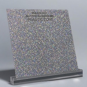 May include: A silver glitter sheet with the text "PLASTICAST GLITTER RAINBOW 009 PLASTIC ZONE" on the top.