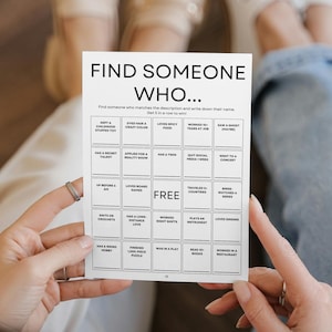 Op de afbeelding: Een persoon houdt een witte kaart vast met de tekst "Find Someone Who..." en een raster van 25 vierkanten. Elk vierkant bevat een andere activiteit of eigenschap, zoals "Is dit jaar naar een concert geweest" of "Kan een muziekinstrument bespelen".