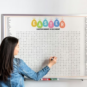 May include: A white framed Easter-themed word search puzzle with colorful egg graphics and the text "Easter Bunny & Egg Hunt." A person is writing on the board with a black marker. The board is on a white wall.