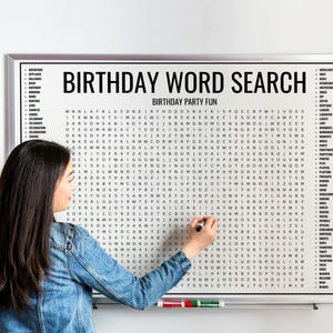 May include: A framed "BIRTHDAY WORD SEARCH" puzzle with the text "BIRTHDAY PARTY FUN" above the word search grid. A person is writing on the board with a black marker. The board is white with a silver frame.