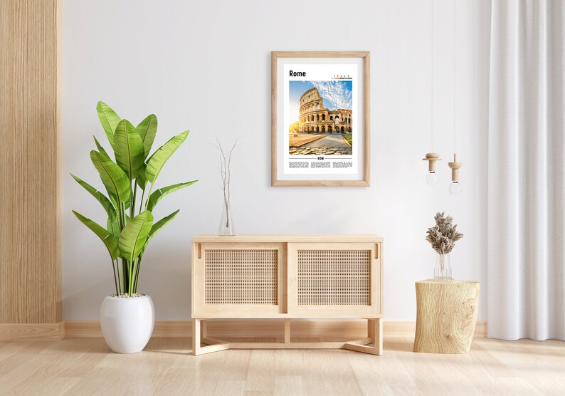 May include: A framed print of the Colosseum in Rome, Italy. The print is in a light wood frame and is hanging on a white wall. There is a wooden cabinet with woven doors and a wooden stool with a vase of dried flowers on it.