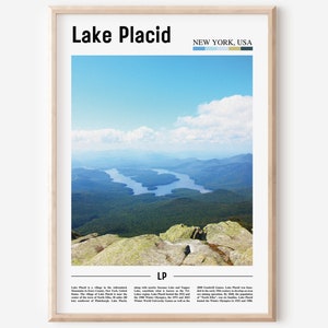Puede incluir: Un póster con una fotografía de una cordillera montañosa y un lago en la distancia. El póster tiene el texto "Lake Placid" en negrita en la parte superior y "NEW YORK, USA" en una fuente más pequeña debajo. El póster también incluye una paleta de colores azul, verde y marrón.