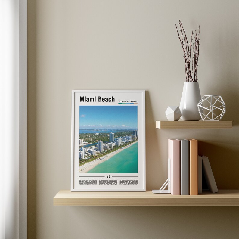 May include: A white framed poster with a black and white image of Miami Beach, Florida. The poster has the text "Miami Beach" and "Miami, Florida" in black text. The poster also has the text "MB" in black text.