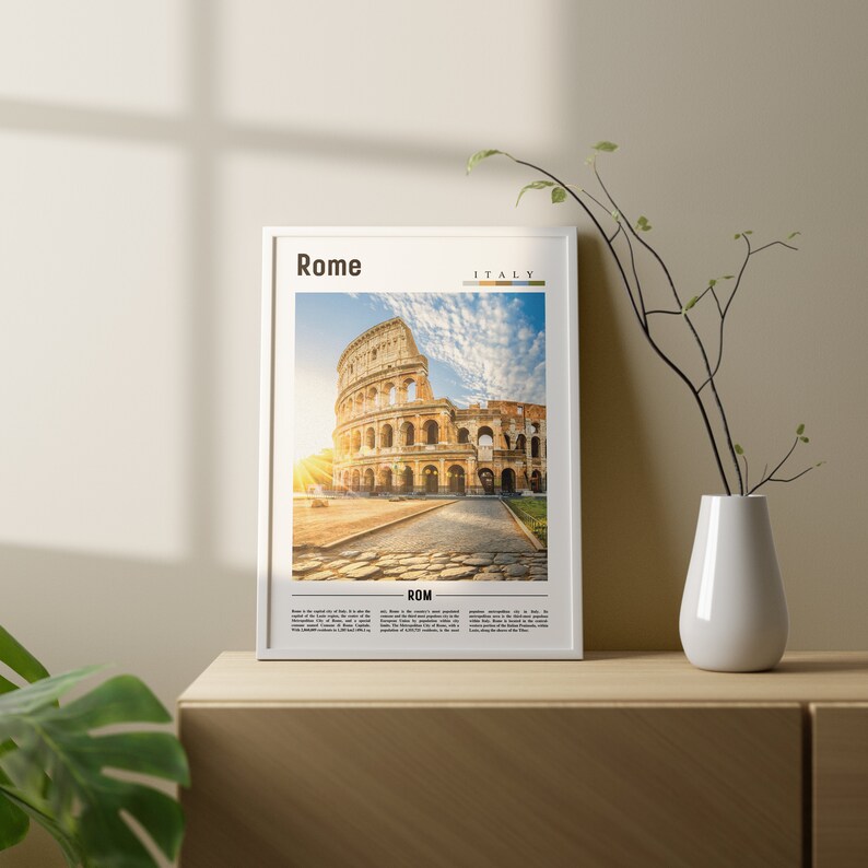 May include: A framed print of the Colosseum in Rome, Italy. The image shows the ancient amphitheater with a bright blue sky and white clouds. The text "Rome" and "Italy" are printed at the top of the frame, and the text "ROM" is printed at the bottom.