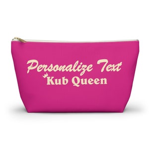 Könnte beinhalten: Eine pinkfarbene Kosmetiktasche mit Reißverschluss und einem weißen Reißverschluss-Zipper. Die Tasche hat den Text "Personalisieren Sie den Text" und "Kub Queen" in cremefarbener Schrift.