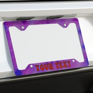 May include: Purple and blue tie-dye license plate frame with silver mounting holes and the text "YOUR TEXT" in red.