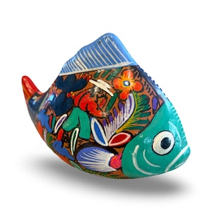 May include: A hand-painted ceramic fish figurine. The fish features a turquoise head, a blue dorsal fin, and a red tail. The body is decorated with colorful floral and abstract designs in red, green, blue, and white.