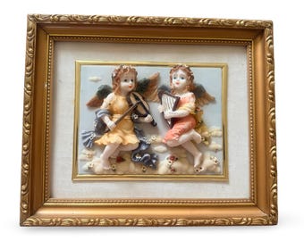 Escultura de ángel en relieve vintage enmarcada, querubines musicales, marco barroco dorado.